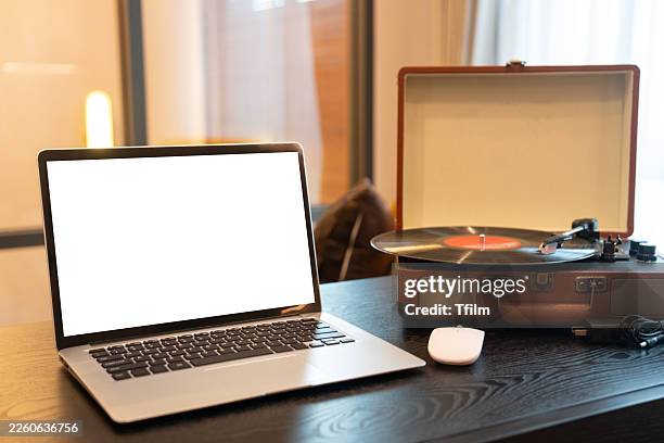 laptop computer with blank screen on desk next to vintage record player - achatar la curva de epidemia fotografías e imágenes de stock