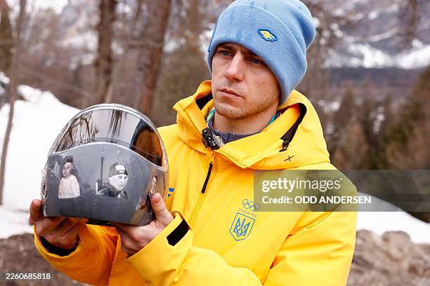 Ukraine's skeleton racer Vladyslav Heraskevych holds his helmet, which depicts victims of his country's war with Russia, in Cortina d'Ampezzo on...