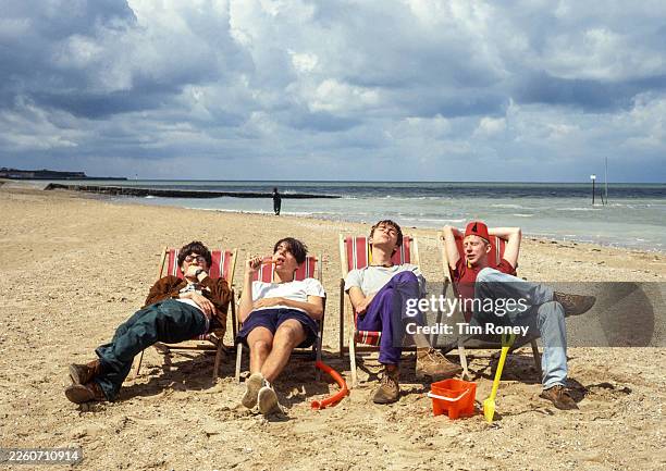 British indie rock band Blur sitting on deckchairs on the beach at Margate, United Kingdom, 1991. L-R Graham Coxon, Alex James, Damon Albarn, Dave...