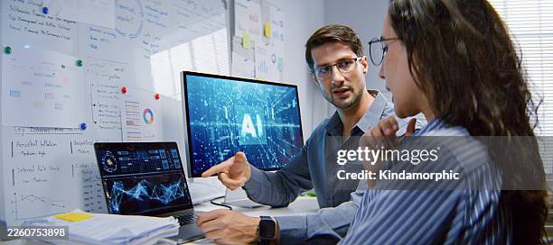 white latin male and female programmer engineer use ai software on laptop computer, meeting discussion at home office at night. internet information technology, artificial intelligence at work concept - virtual assistant stock pictures, royalty-free photos & images
