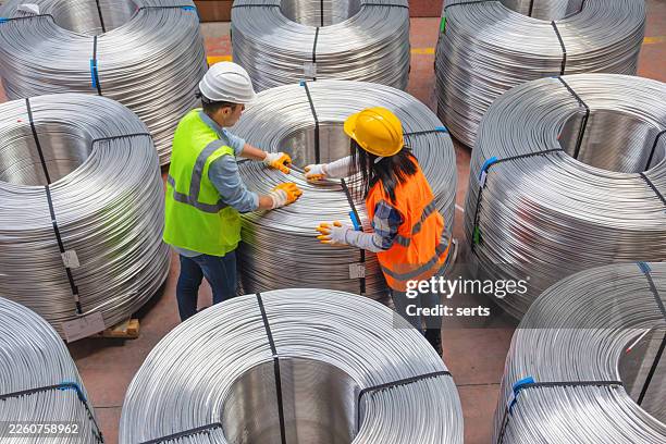 high angle view of industrial workers inspecting large steel wire coils inventory in factory warehouse - steel stock pictures, royalty-free photos & images