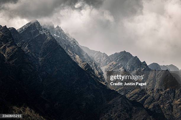 a dramatic long lens landscape view onto the remarkables mountain range near queenstown, on the south island of new zealand - rock face stock pictures, royalty-free photos & images