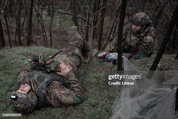 Two wounded Ukrainian soldiers from the 5th Separate Assault Brigade lie on a road between Druzhkivka and Kostyantynivka awaiting evacuation as...