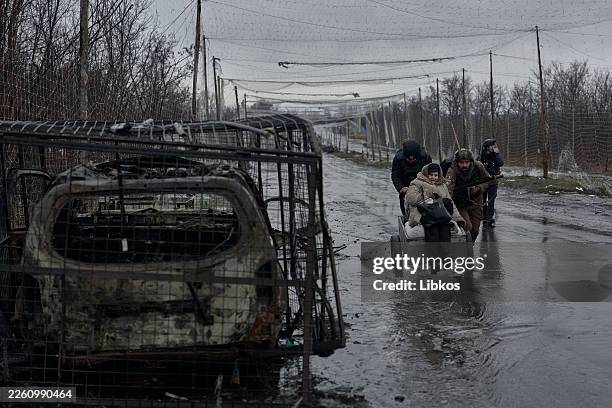 Local residents leave the city of Kostyantynivka alongside volunteers, walking beneath protective nets installed above the road to shield against...