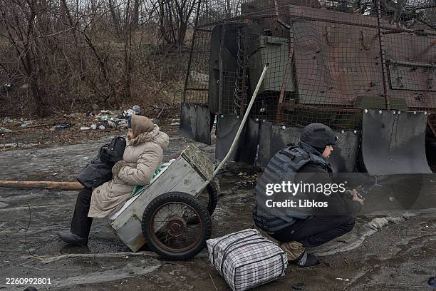 Volunteer and an elderly woman rest beside a destroyed armored vehicle along the road near Kostyantynivka as evacuation efforts continue under the...