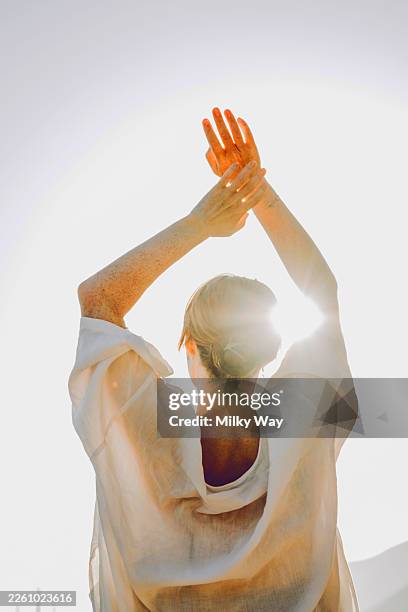 woman raising hands in sunlight outdoors with serene posture. - artista imagens e fotografias de stock