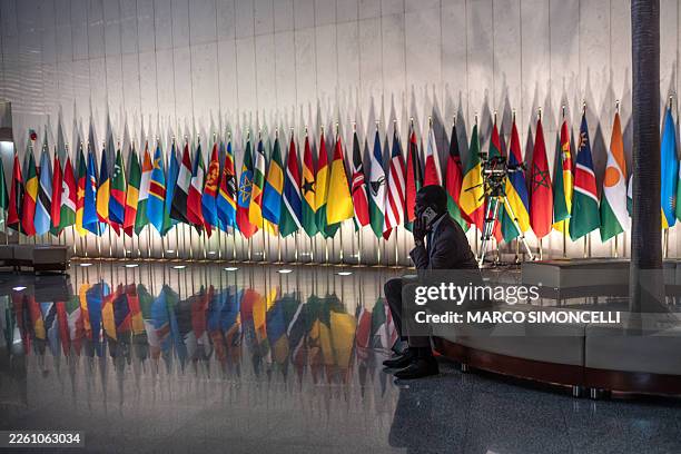Delegate sits on a couch in front of a row of flags of African Union member states inside the African Union Headquarters ahead of the opening of the...