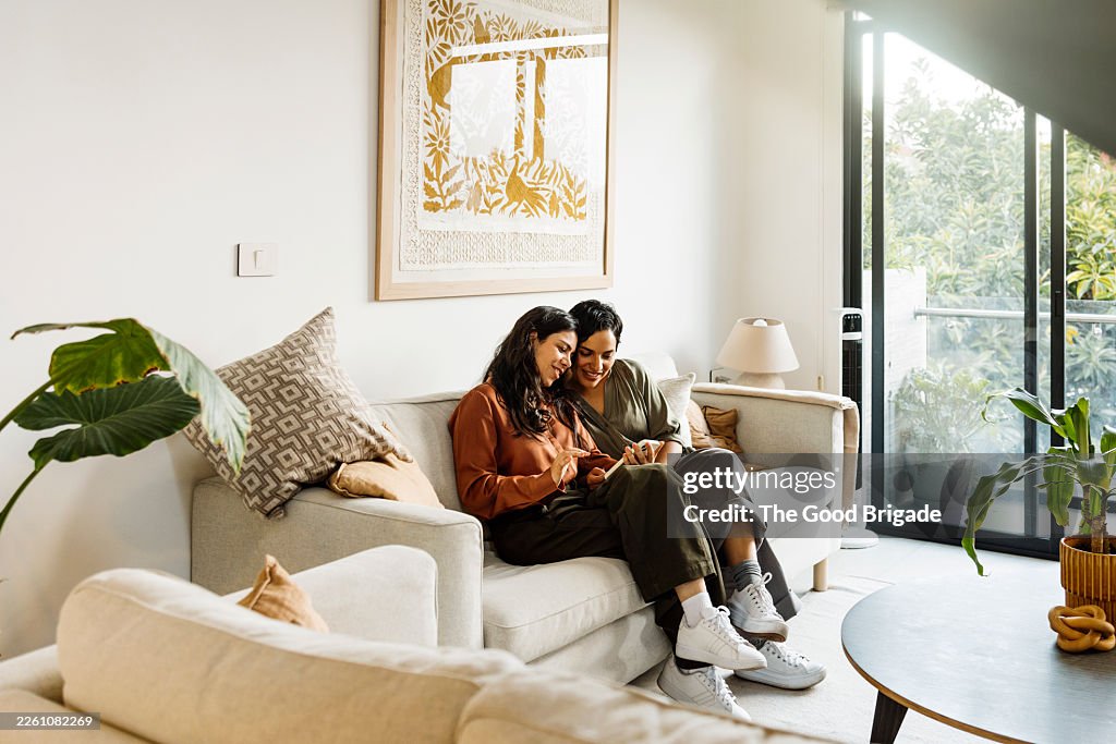 Lesbian couple using smart phone for video call while sitting on sofa