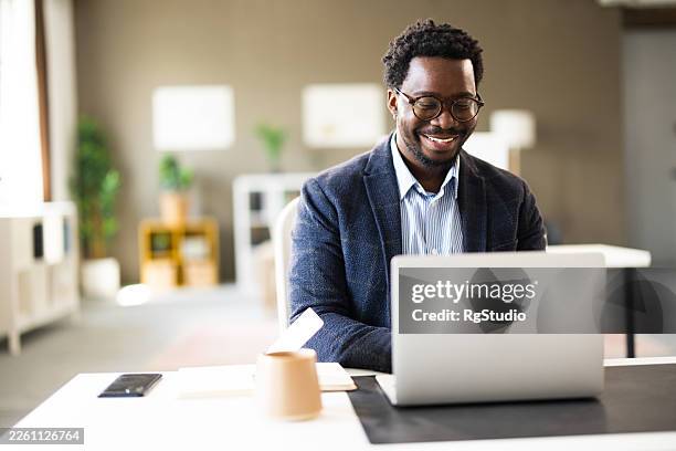african american businessman smiling working on laptop in office - workplace training stock pictures, royalty-free photos & images