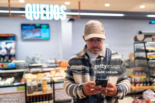 man using cell phone at supermarket - modern manhood stock pictures, royalty-free photos & images