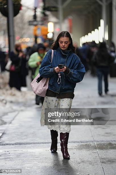 Guest wears a pink leather bag, a pink hair clip, purple and yellow rings, a blue denim high neck zipper jacket, a brown knit sweater / pullover, a...