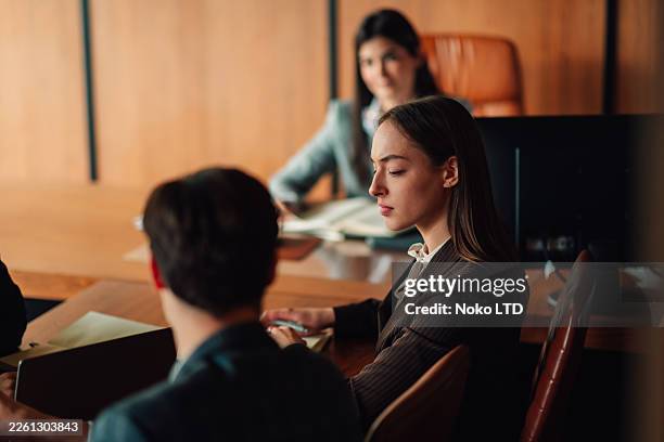 giovane donna adulta che partecipa a una riunione d'affari o a un procedimento legale, concentrata e attentamente in sala conferenze - studio legale foto e immagini stock