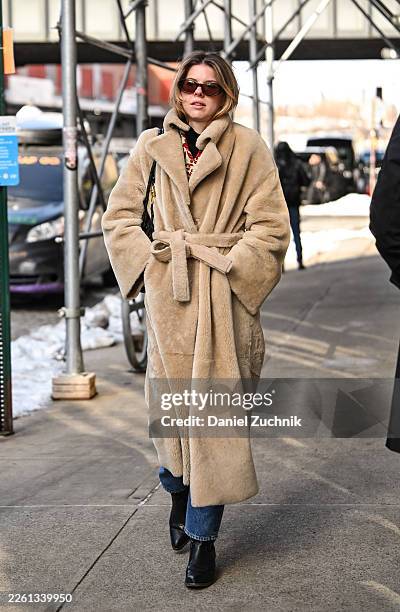 Guest is seen wearing a tan faux fur coat, blue jeans, black boots and sunglasses outside the Carolina Herrera show during New York Fashion Week...