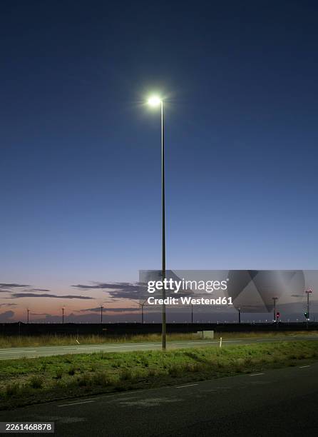 lamppost and wind turbines at night in rotterdam harbour - pole stock pictures, royalty-free photos & images