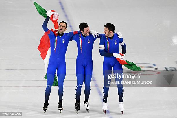Italy's Andrea Giovannini, Italy's Michele Malfatti and Italy's Davide Ghiotto celebrate with Italian flags after winning gold in the speed skating...