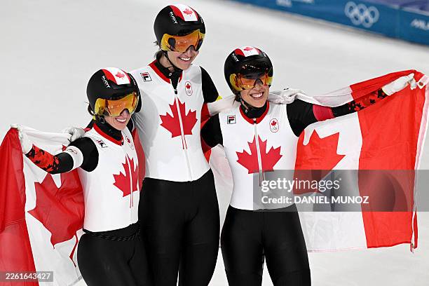 Canada's Ivanie Blondin, Canada's Isabelle Weidemann and Canada's Valerie Maltais pose with Canadian flags after winning gold in the speed skating...