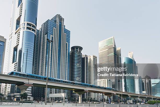 low view of dubai downtown business district with skyscapers and office buildings and metro train on outdoors rail - gulf countries stock pictures, royalty-free photos & images