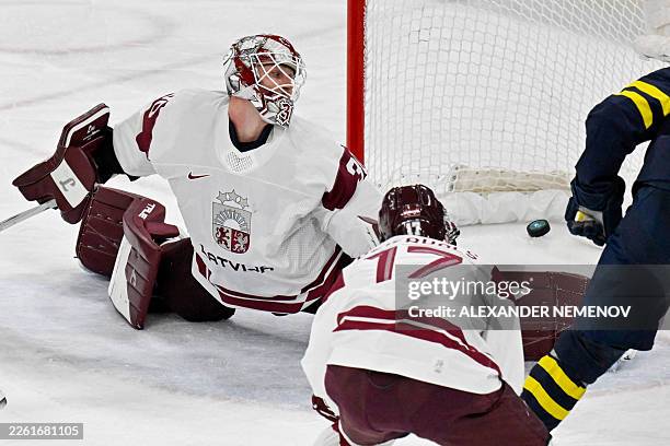 Latvia's Elvis Merzlikins concedes the third goal by Sweden during the men's qualification play-off ice hockey match between Sweden and Latvia at the...