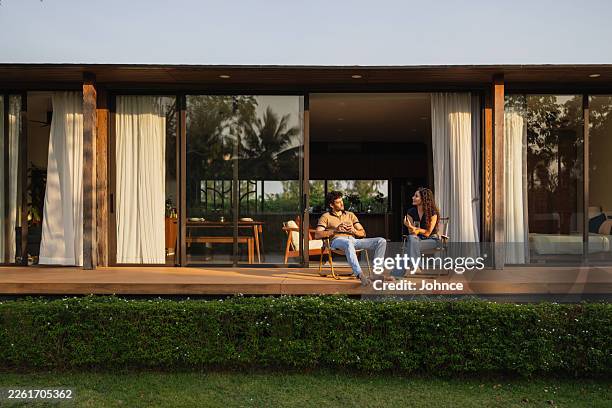 couple relaxing on the deck of a modern house - golden hour stock pictures, royalty-free photos & images