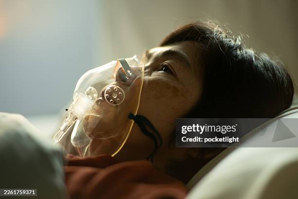mature woman using oxygen mask for respiratory therapy. - nebulizer stock pictures, royalty-free photos & images