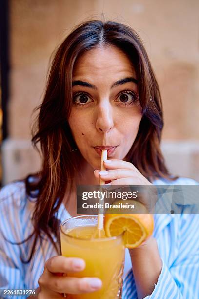 young woman enjoying refreshing orange juice with wide eyes - straw stock pictures, royalty-free photos & images
