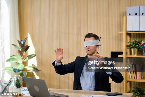 blindfolded businessman navigating corporate cyber security risks - ignorancia fotografías e imágenes de stock