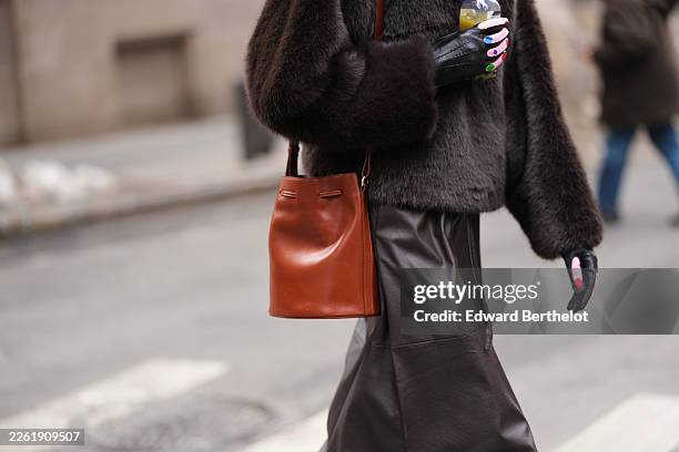 Guest wears brown leather shoulder bag, black faux fur high neck jacket, black shiny leather with multicolored painted pattern gloves, black leather...