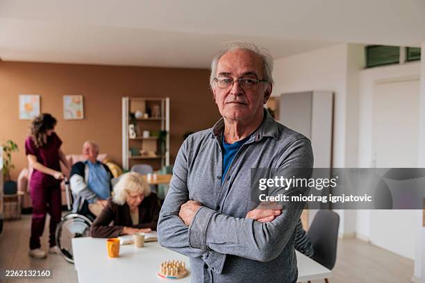 confident senior man standing in nursing home common room - retirement community stock pictures, royalty-free photos & images