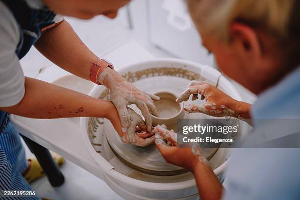 close-up of instructor guiding woman’s hands on pottery wheel - pottery wheel stock pictures, royalty-free photos & images