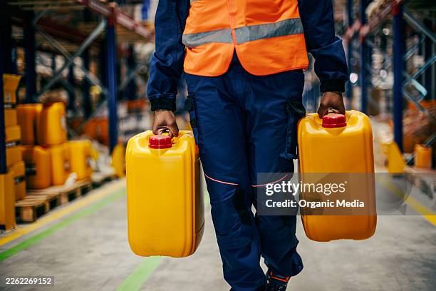 worker carrying chemical canisters inside industrial warehouse - canister stock pictures, royalty-free photos & images