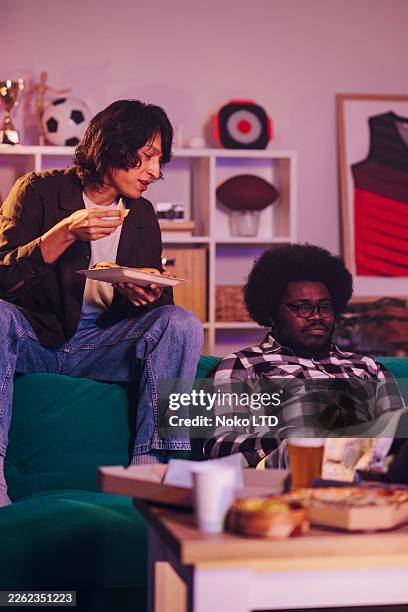 des amis à la maison, mangeant de la pizza et des snacks en regardant la télé ou en jouant aux jeux vidéo - amitié masculine photos et images de collection