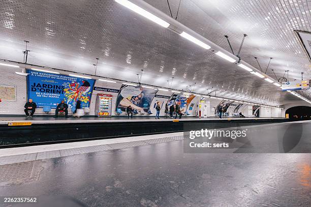 passagers attendant sur le quai de la station de métro colonel fabien paris avec des affiches publicitaires et une architecture de tunnel carrelé courbé à paris, france - entrée metro paris photos et images de collection