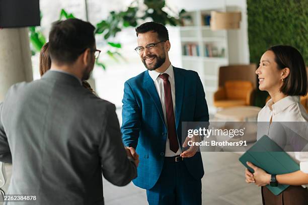partner commerciali che stringono la mano in un ufficio moderno - completo da uomo foto e immagini stock