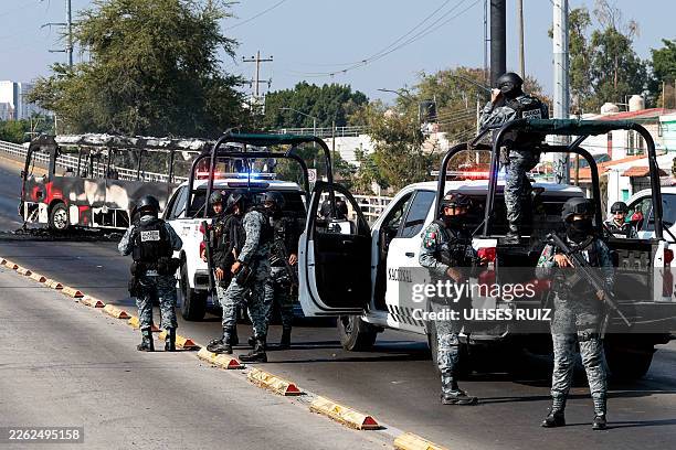 National Guard members stand guard near a burnt bus set on fire by organised crime groups in response to an operation in Jalisco to arrest a...