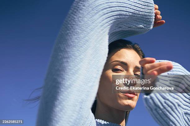woman protecting eyes from sun on clear sky day - shielding face stock pictures, royalty-free photos & images