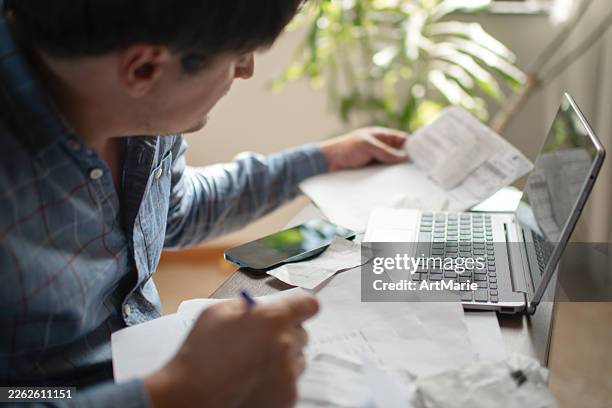 man with laptop and financial documents - debt stock pictures, royalty-free photos & images