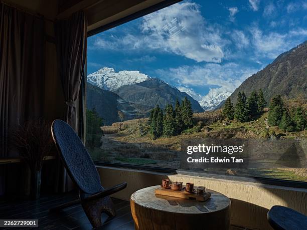tea set on wooden table overlooking snow-capped mountain landscape through large window - log cabin stock pictures, royalty-free photos & images