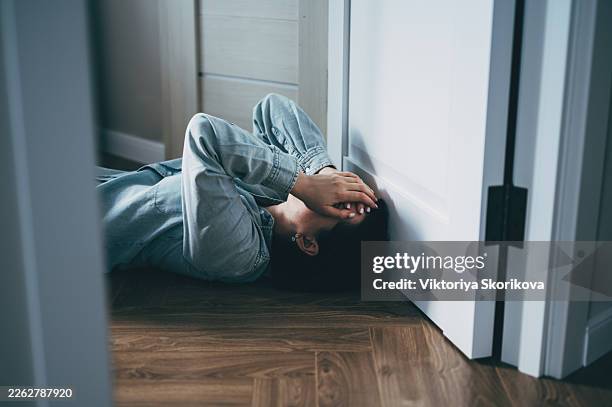 depressed woman sitting on floor covering face with hands in despair - suicide imagens e fotografias de stock