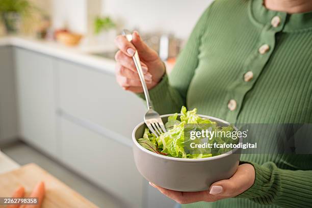 persona desconocida sosteniendo un bol de ensalada de lechuga recién hecha en casa. alimentos crudos, bajos en carbohidratos o dieta basada en plantas. comer y comer sano en la cocina - ensalada verde fotografías e imágenes de stock