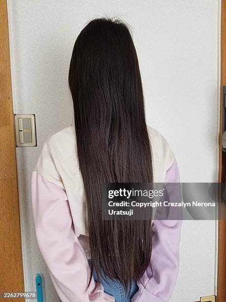 silky length. a young girl stands with her back to the camera,in front of electric switch - straight hair stock pictures, royalty-free photos & images