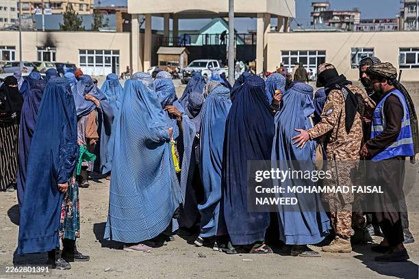 Afghan burqa-clad women queue to receive food aid from a local charity during the Islamic holy fasting month of Ramadan in Ghazni on February 24,...