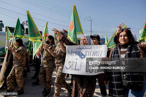 Woman holds a handwritten sign while participants gather during a protest in Qamishli, Syria on February 23 calling for the protection of the gains...