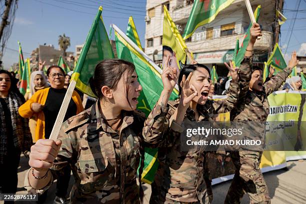 Women flash victory signs and wave YPJ flags during a protest in Qamishli, Syria on February 23 calling for the protection of the gains of the...