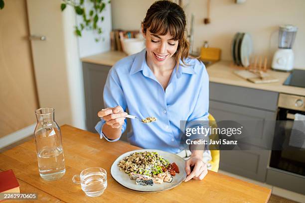 woman enjoying healthy meal with fresh salmon in kitchen - omega 3 stock pictures, royalty-free photos & images
