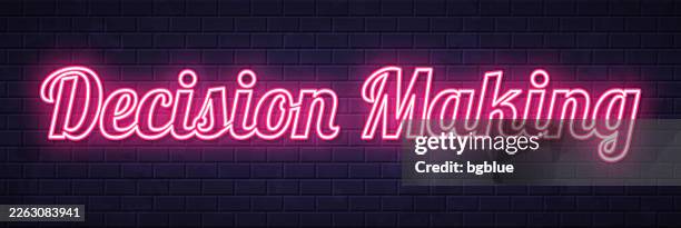 decision making - glowing neon text on brick wall background - make decision stock illustrations