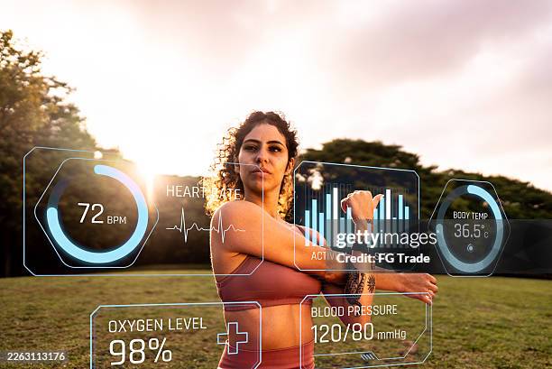 young woman with smartwatch analyzing data with augmented reality while exercising outdoors - wearable computer stock pictures, royalty-free photos & images