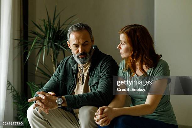reifes paar, das zu hause auf dem sofa sitzt. - partnertrennung stock-fotos und bilder