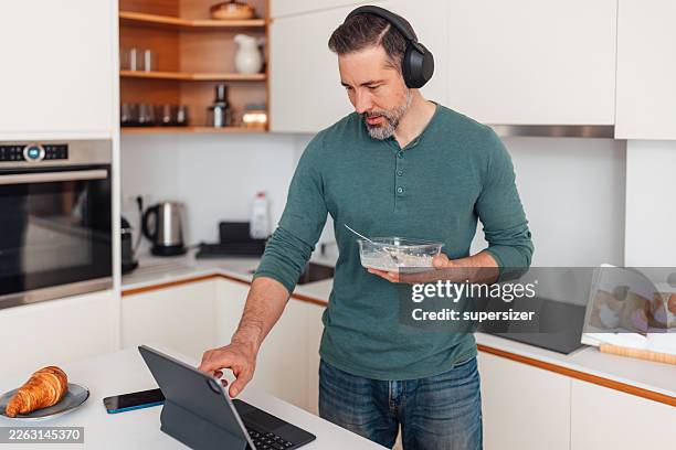 man multitasking while enjoying breakfast at home - multi task stock pictures, royalty-free photos & images