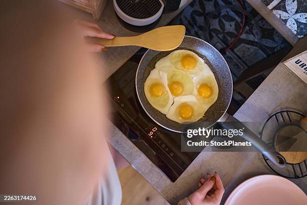 person cooking fried eggs on induction stovetop - frying pan stock pictures, royalty-free photos & images