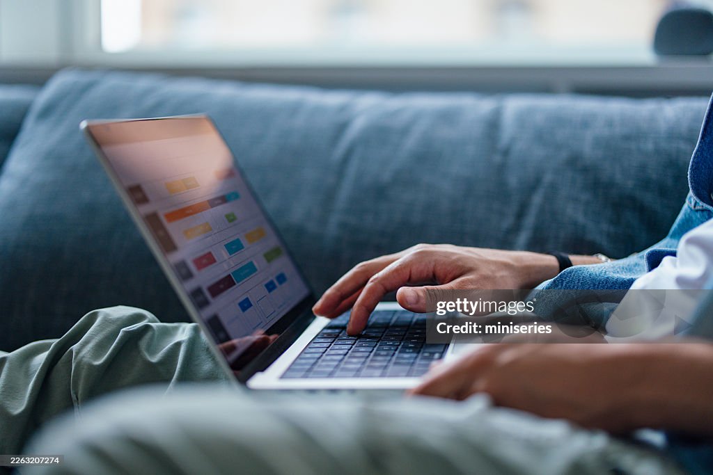 Man Working at Home on Laptop in Casual Manhattan Apartment Couch